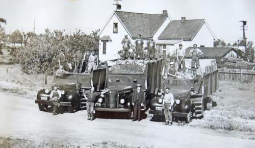The Peninsula Sanitary Service crew in the 1930s. Luigi is pictured standing in the middle on top of the second truck, and Andrew is pictured sitting on the left side of the truck on the left.